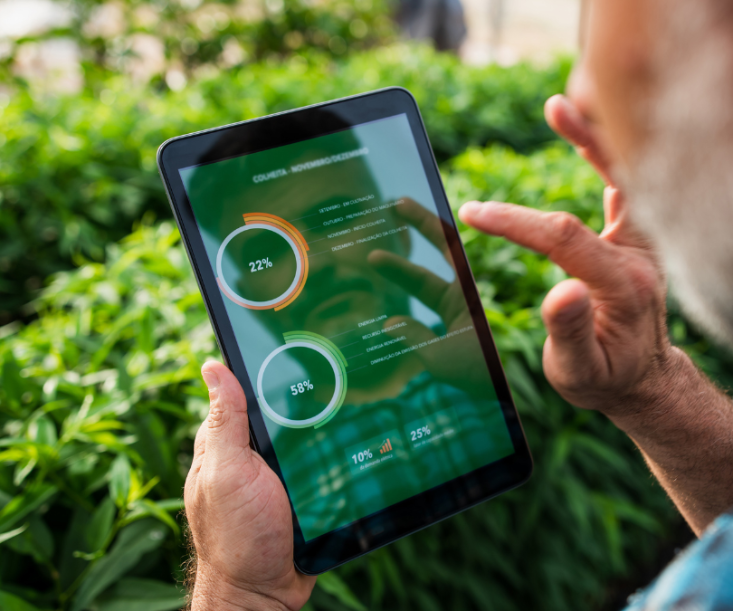 Mann steht im Feld und schaut sich Auswertungen auf einem Tablet an